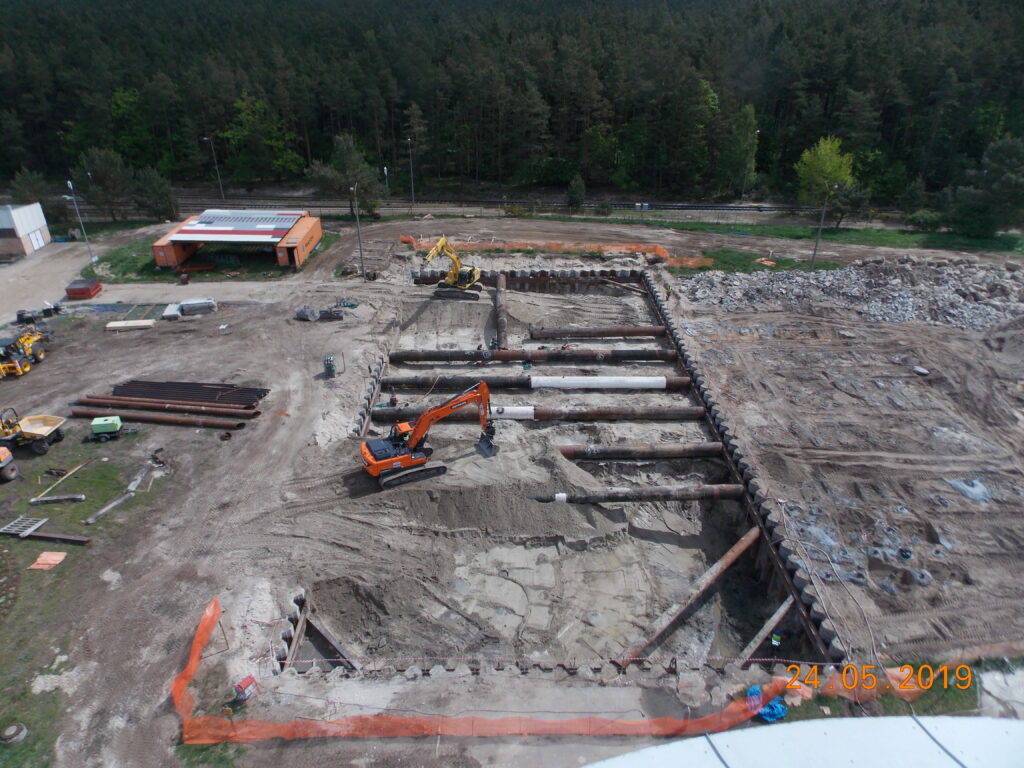 Wykop pod nowe obiekty oczyszczalni, w tle las.